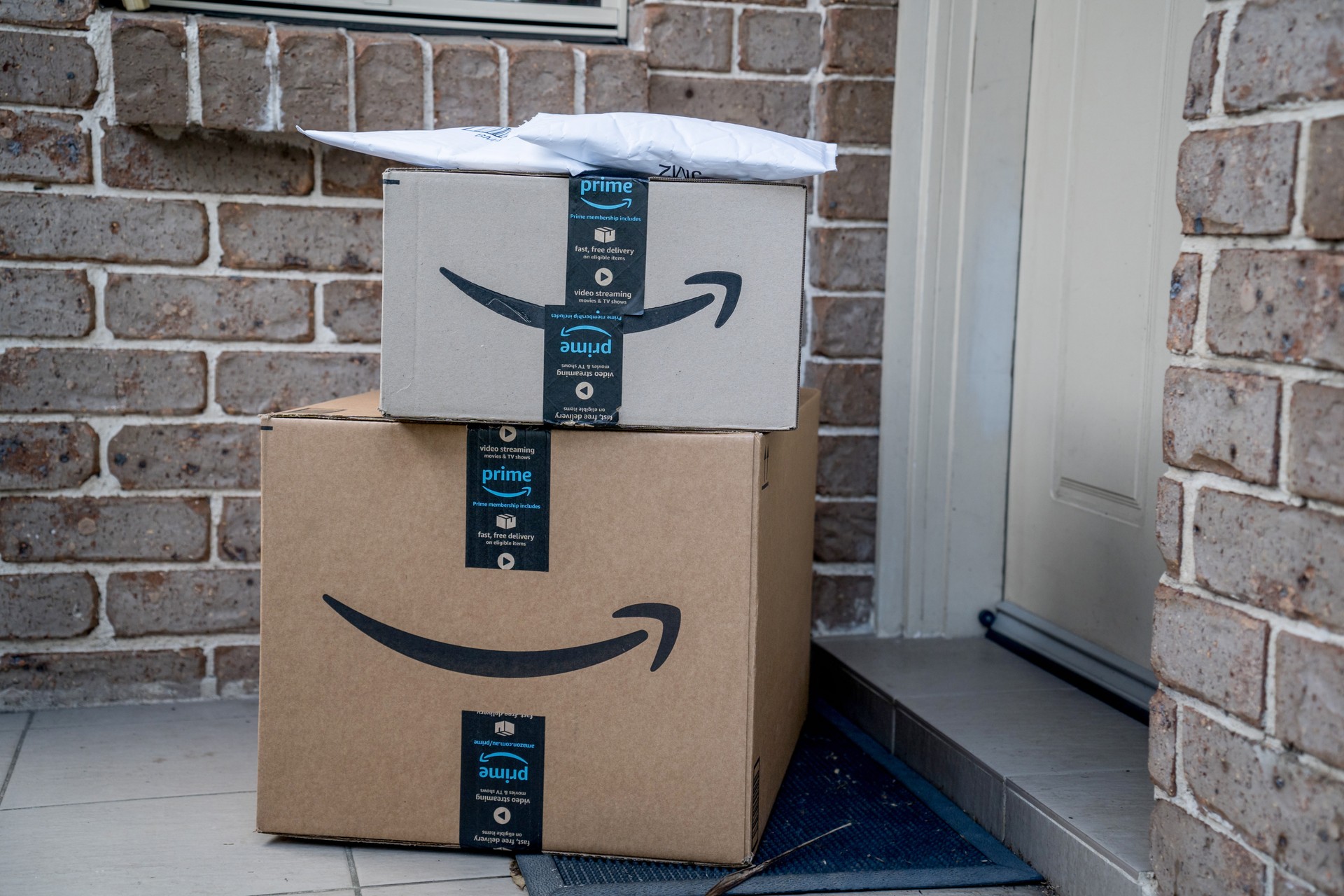 Amazon prime boxes and envelopes delivered to a front door of residential building